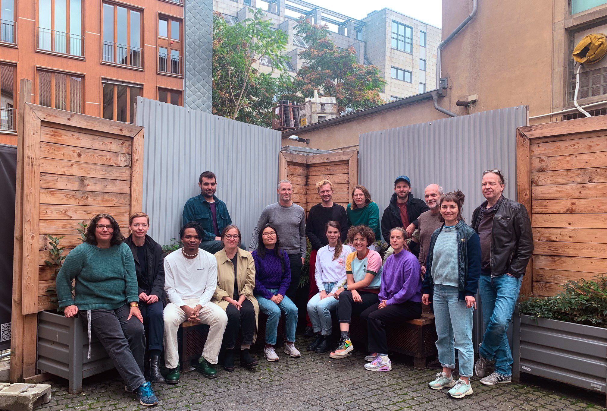 Das Team der Kulturraum Berlin gGmbH in einem Gruppenfoto, einige sitzen, andere stehen. Das Foto ist auf einem Innenhof entstanden